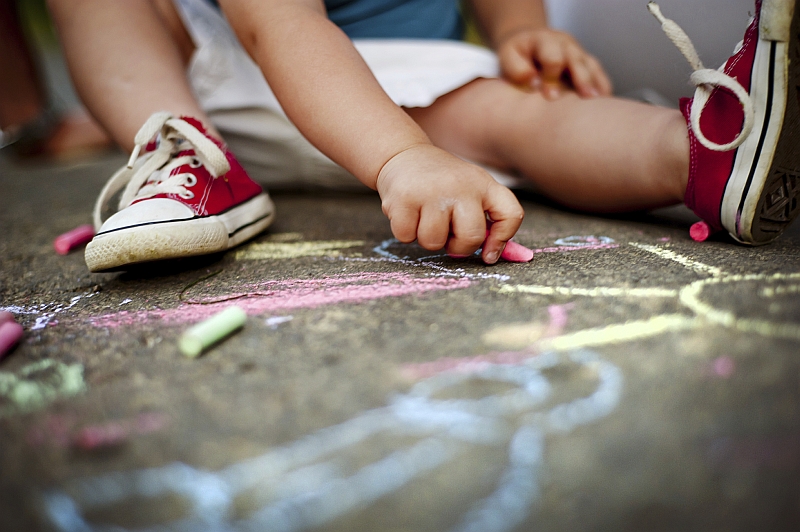 Kind malt mit Kreide auf Boden