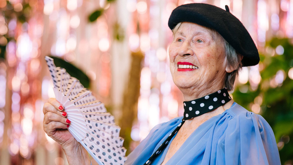 Seniorin mit Barret und Fächer im blauen Seidenkleid