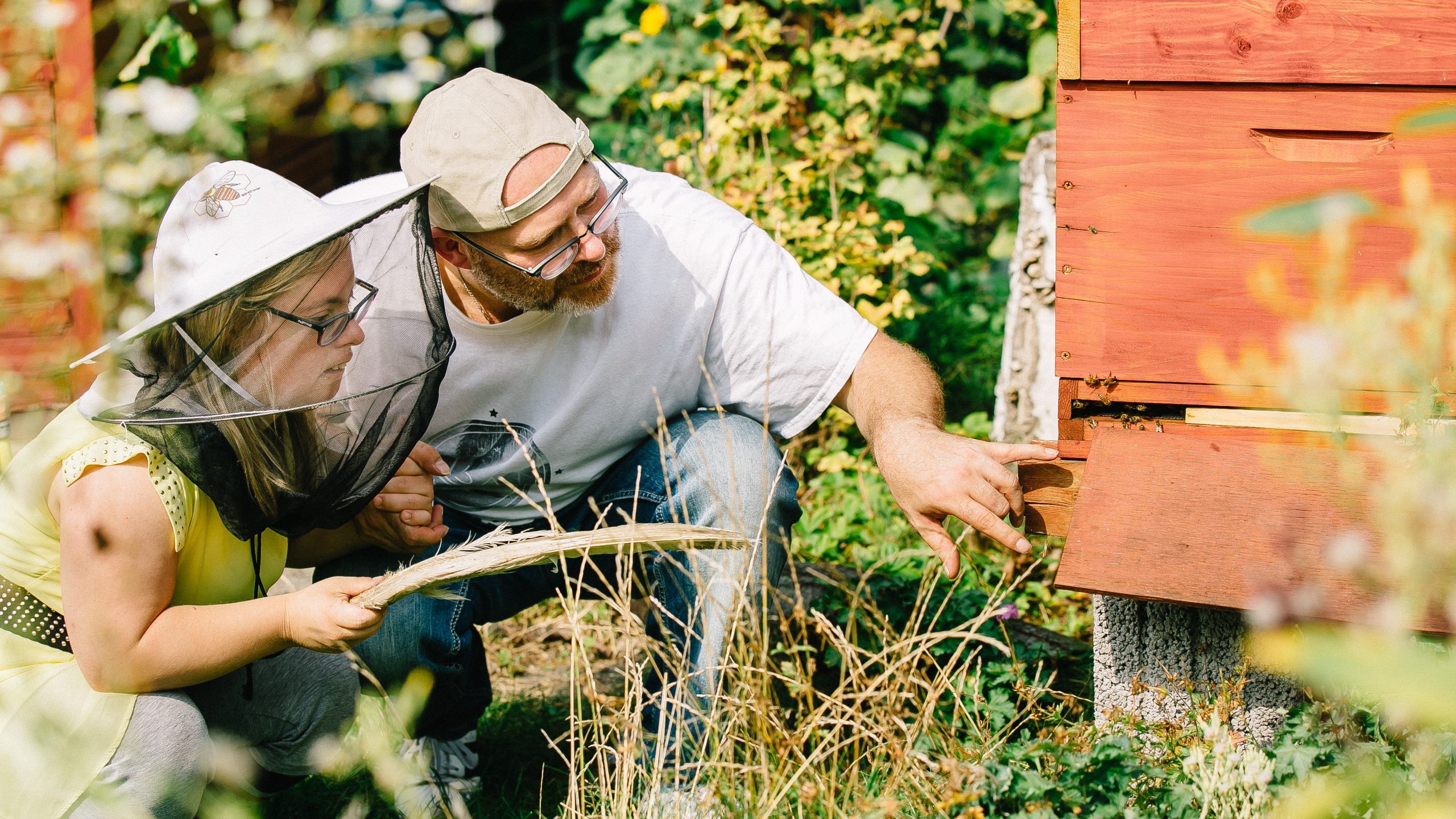 zwei Personen vor Bienenstock draußen