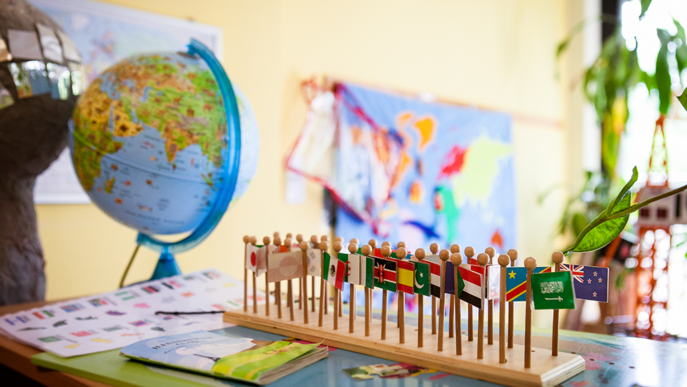 kleine Holzflaggen auf Tisch im Hintergund Globus und Weltkarte
