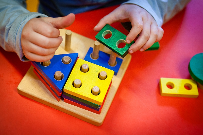 Kinderhände spielen mit Holzspielzeug