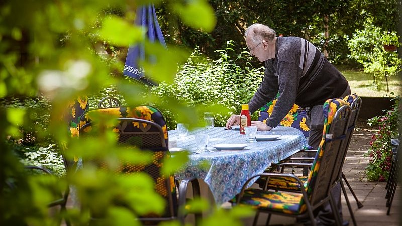 Mann deckt draußen Tisch