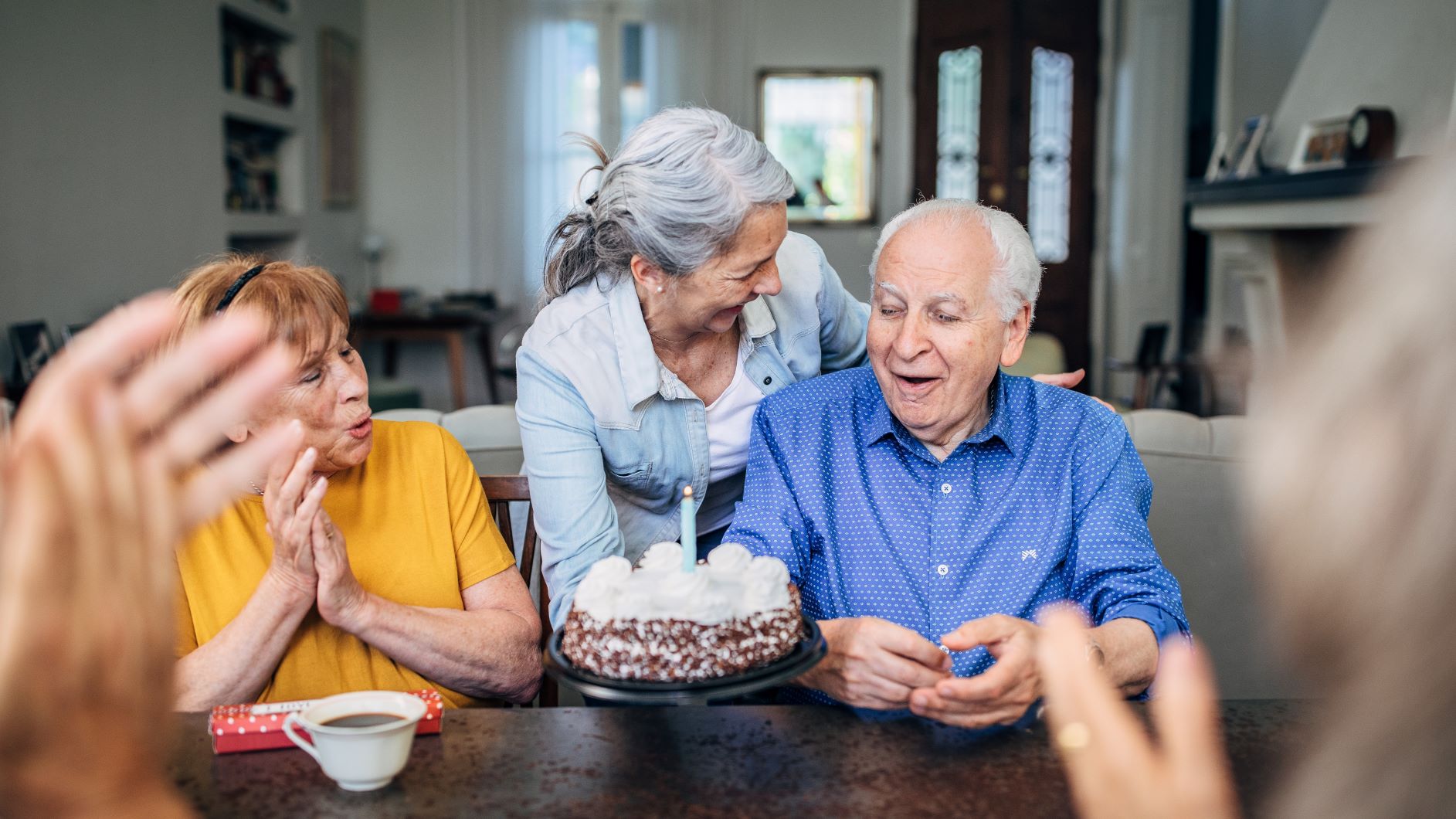 ältere Menschen am Tisch eine Frau hält eine Torte mit Kerze