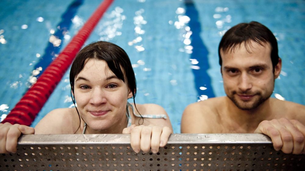 Mann und Frau schauen aus dem Schwimmbecken