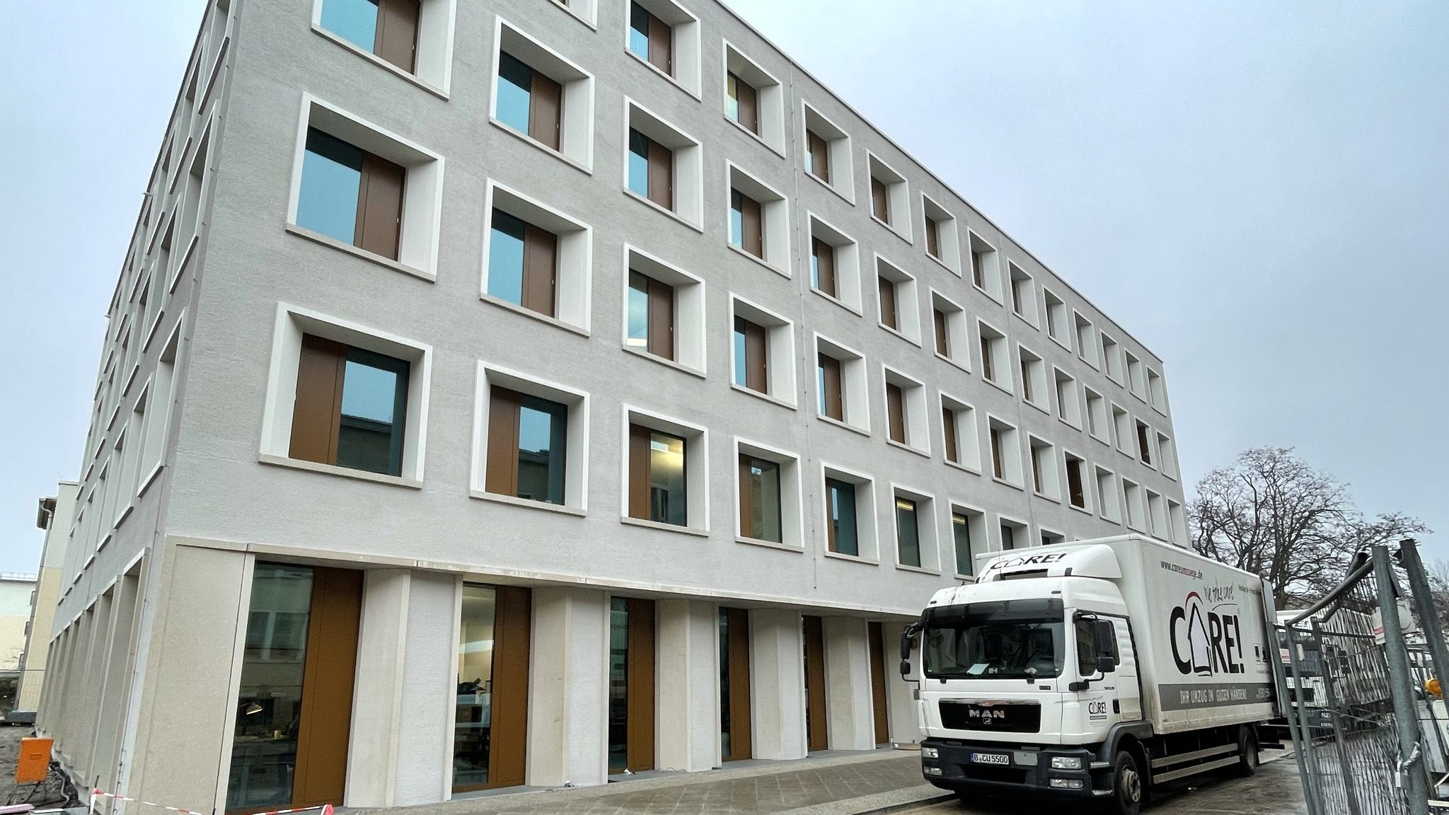 Goßes Haus mit vielen Fenstern. Davor steht ein LKW.